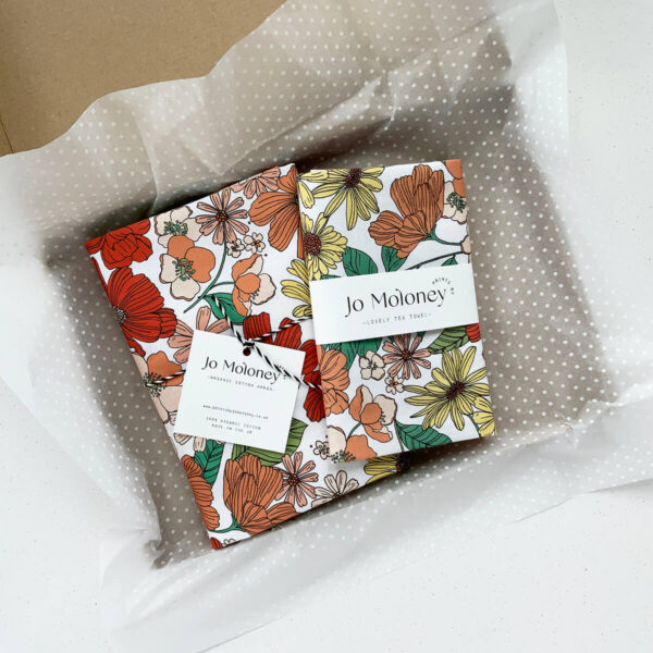 Peach floral tea towel and apron in packaging ready to post